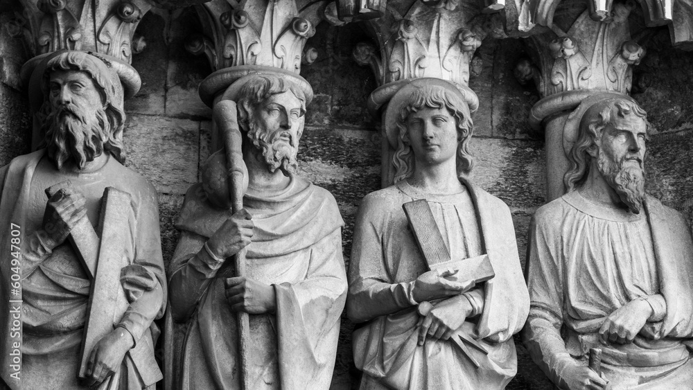 Sculptural images of the Holy Apostles on the wall of the facade of Saint Fin Barre's Cathedral in Cork, Ireland. The Apostles Andrew, James major, Thomas, Matthias. Black and white. Monochrome.