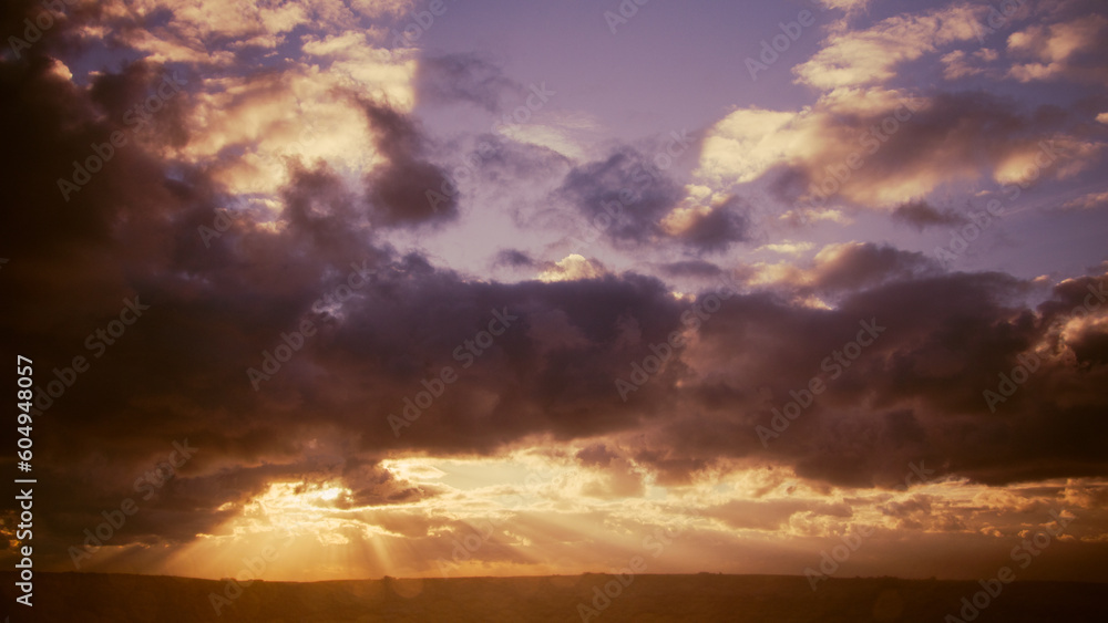 Pink dawn. The sun's rays break through the clouds. Dramatic sunset sky with clouds and sunbeams, nature background