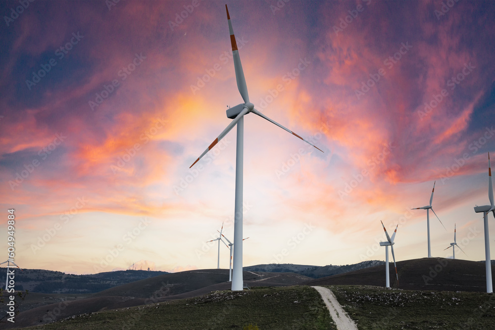 Obraz premium 4k Time lapse of turbines of a wind farm in the Italian mountains in a romantic and cloudy sunset. Conceptual video to represent the energy of technology, the environment and life in the open air.