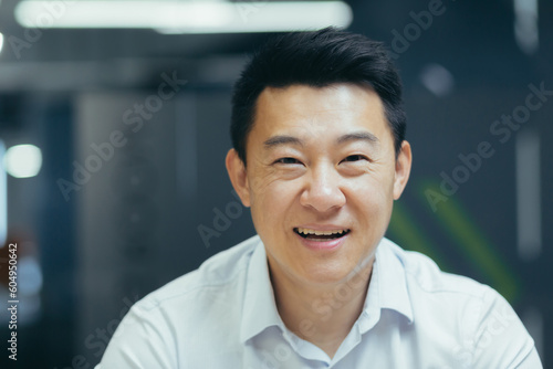 Close-up photo of a young Asian businessman, accountant, manager in the office smiling at the camera.