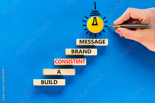 Consistent brand message symbol. Concept words build a consistent brand message on wooden blocks. Businessman hand. Beautiful blue background. Business consistent brand message concept. Copy space. photo