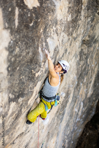 woman climbing big walls in the mountains, doing sports, striving hard for her goals without fear of success, courageous person, confident person with commitment.