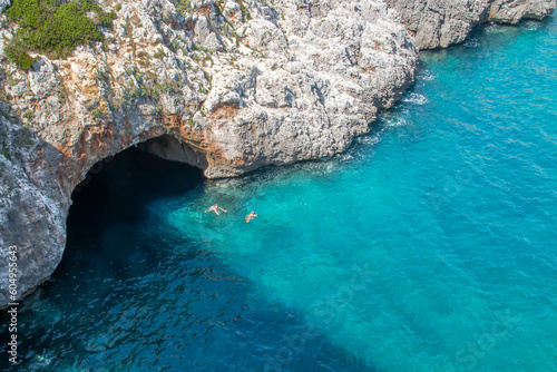 Grotta Grande Del Ciolo, traducción cueva grande del Ciolo, desde el puente del mismo nombre en Gagliano del Capo, Italia. Bañistas haciendo snorkel junto a la entrada en aguas cristalinas.