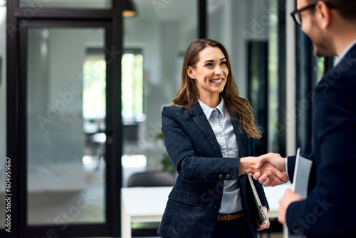 A smiling female employee handshake with a male boss at the office, elegantly dressed.