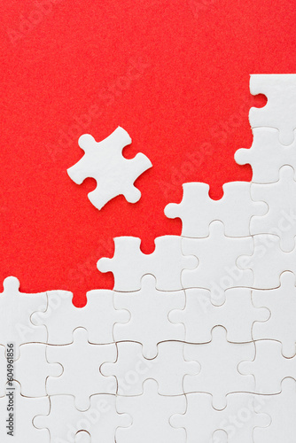 Unfinished white puzzle pieces on red background