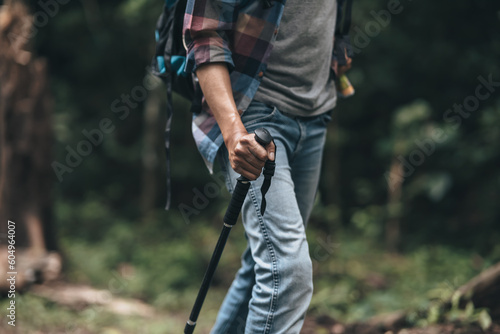 Hikers use trekking pole with backpacks and hold tent bag walking through the forest. hiking and adventure concept.