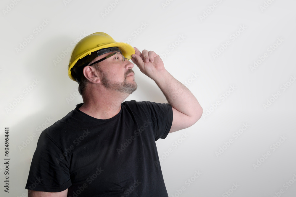 The builder looks at work on the ceiling in a new building. Lighting, puttying, painting of a ceiling