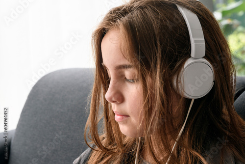 Young girl in headphones, careless close-up portrait. in the house against the background of the window. lifestyle