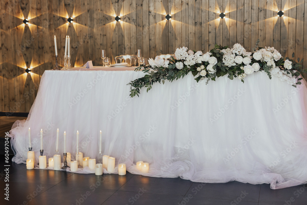 The elegant and classic area of the Newlyweds table is decorated with flowers and candles. Beautiful decoration of the wedding table.