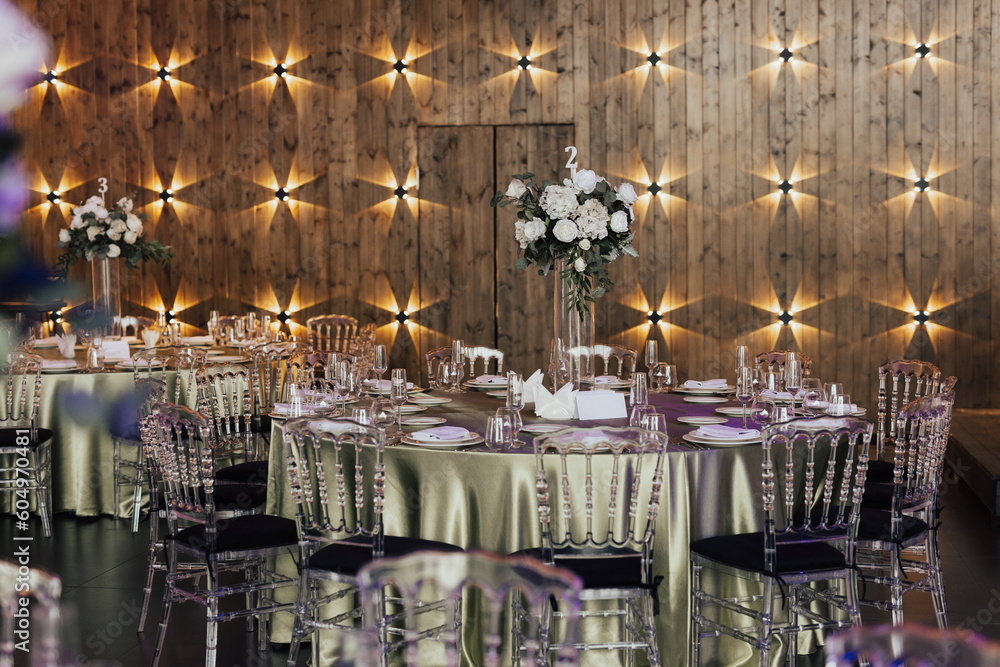 Elegant luxury wedding tables arrangement with green tablecloth, plates, glasses and decoration with flowers.