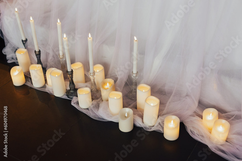 Obraz na płótnie A different candles with a white curtain behind them for decoration at holidays.
w salonie