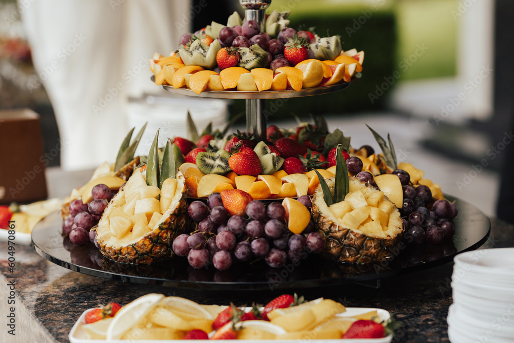 Plate with different kind of fruits. Luxury gorgeous wedding buffet with oranges, grape, pineapple, strawberries and kiwi.