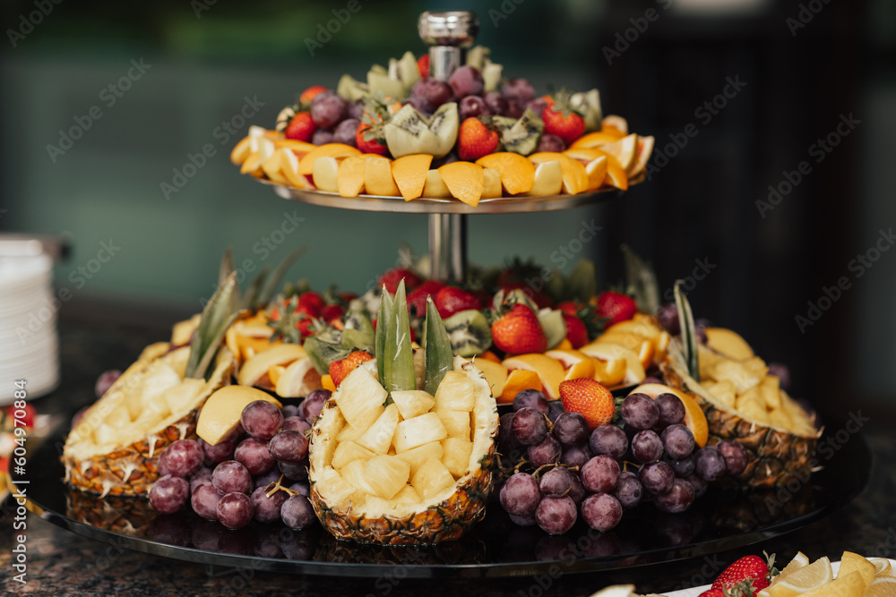 A fruit platter with pineapples, grapes, kiwi, strawberries and oranges on it.