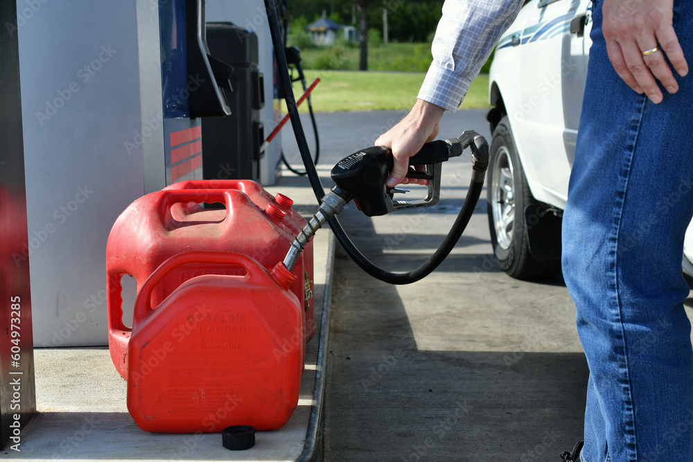 Man pumping gas from a gasoline pump into gas cans to transport it to another location. Man pumping gas from a gasoline pump into gas cans to transport it to another location.