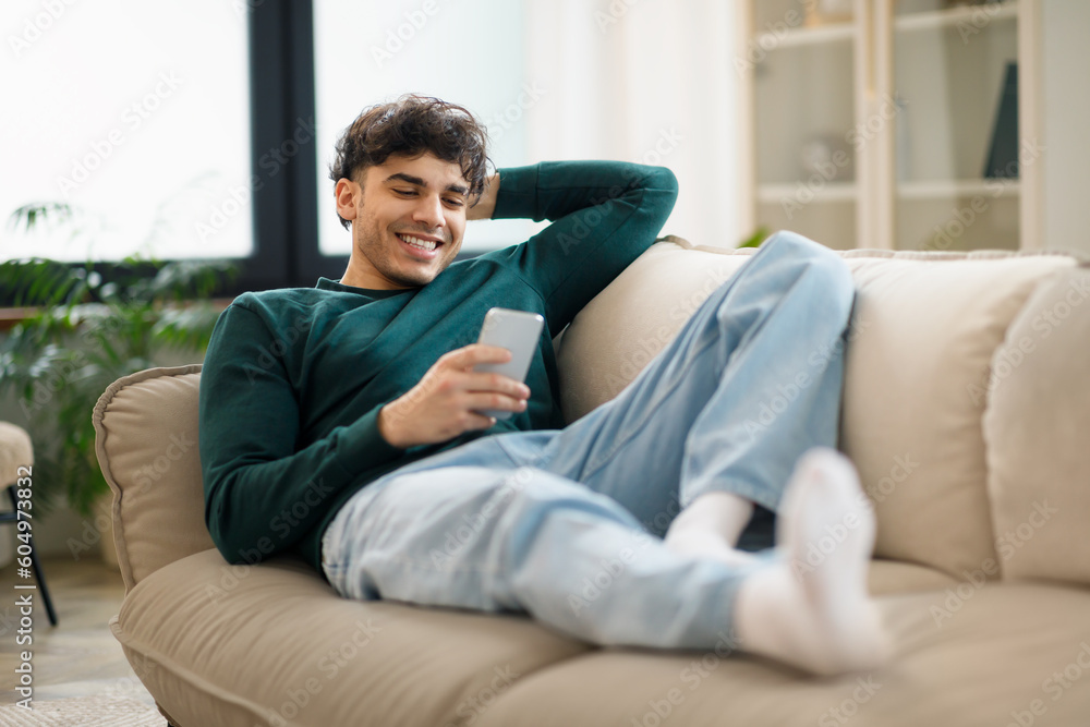 Guy Browsing Internet On Smartphone Lying On Couch At Home Guy Browsing Internet On Smartphone Lying On Couch At Home