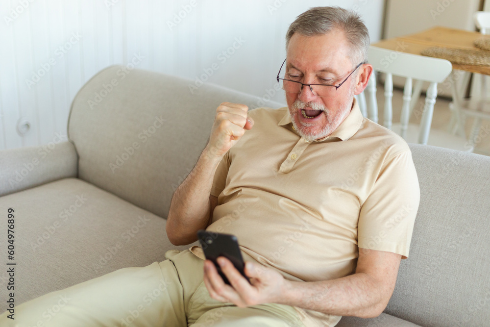 Middle aged senior man euphoric winner with smartphone. Older mature grandfather looking at cell phone reading great news getting good result winning online bid feeling amazed. Winning gesture Middle aged senior man euphoric winner with smartphone. Older mature grandfather looking at cell phone reading great news getting good result winning online bid feeling amazed. Winning gesture