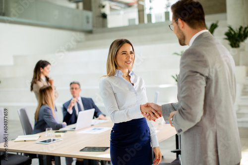 Young business woman handshaking with his colleague in the office