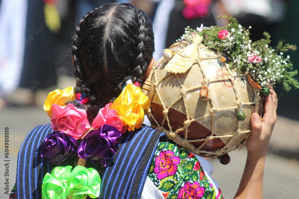 indigenous woman carrying a pitcher decorated with field flowers