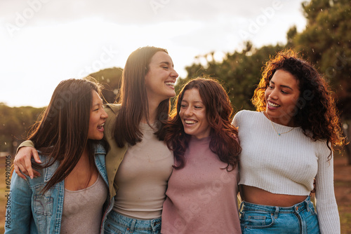 Group portrait of four multiracial young girlfriends walking together.