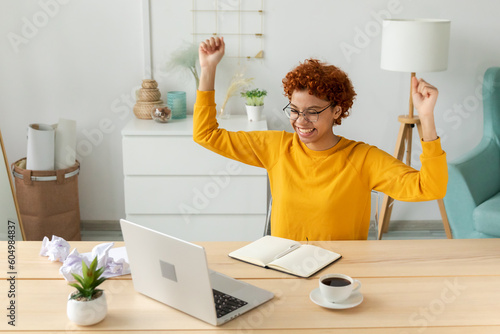 Excited happy african american woman euphoric winner. Girl student looking at laptop passed exam reading great news getting good result winning online bid feeling amazed at home. Winning gesture