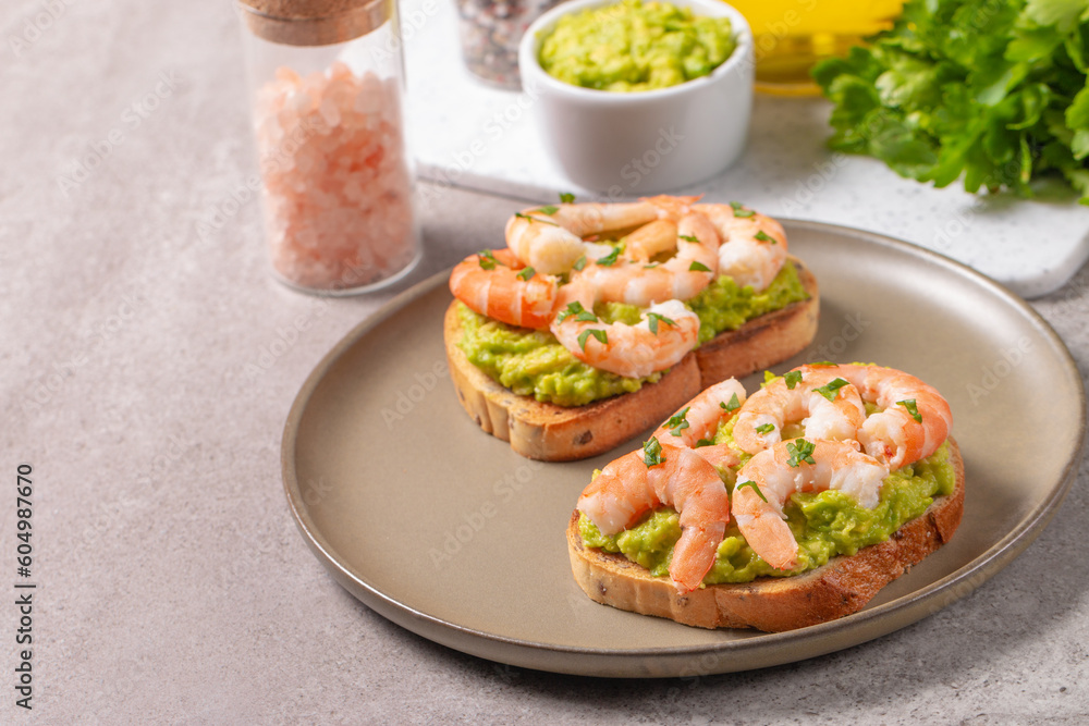 Appetizer toasted bruschetta with mashed avocado and shrimps on background. Healthy food concept with prawns.