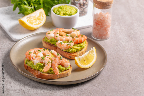 Appetizer toasted bruschetta with mashed avocado and shrimps on background. Healthy food concept with prawns.