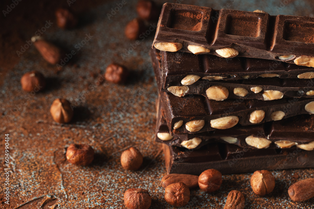 Dark and milk chocolate with nuts on a dark background sprinkled with cocoa powder. Dark and milk chocolate with nuts on a dark background sprinkled with cocoa powder.