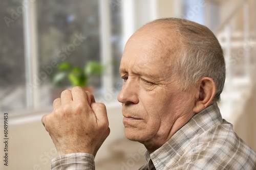 Pensive old man looking in distance of window