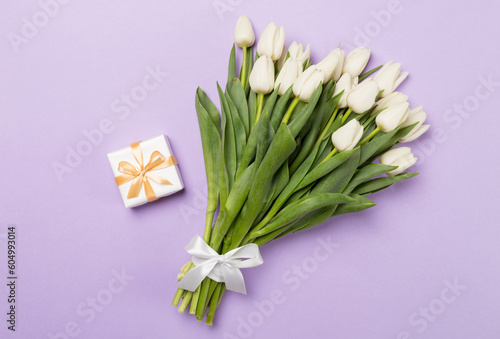 White tulip bouquet with gift on color background  top view