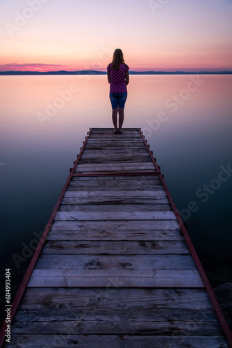 woman standing on pier at sunset