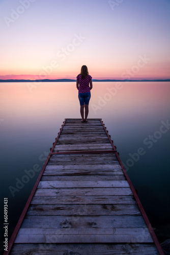 woman standing on pier at sunset