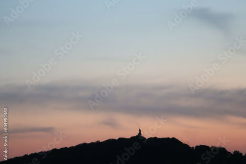 Wieża klasztoru na szczycie góry z zachodem Słońca w tle photo