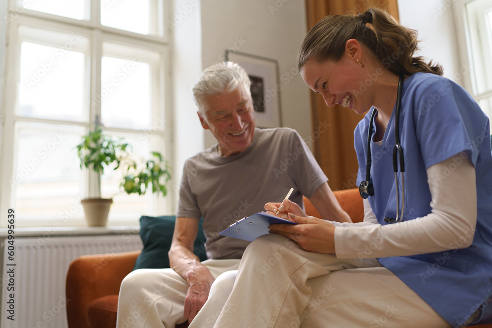 Fototapeta premium Young nurse checking elderly senior in his home.