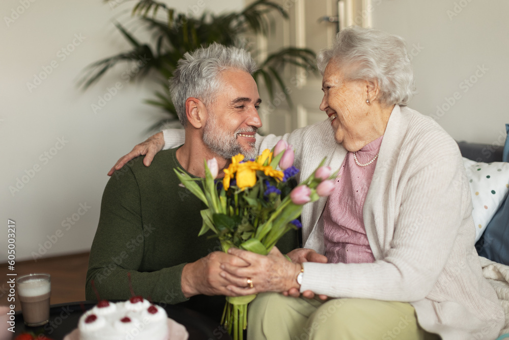 Mature man celebrating with his senior mother at her apartment. Mature man celebrating with his senior mother at her apartment.