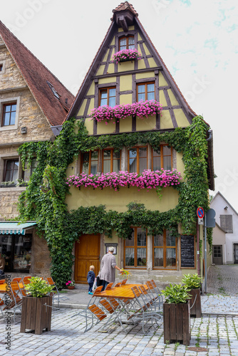 Canvas Print A traditional Bavarian house with pink windowbox flowers over a small cafe, in R