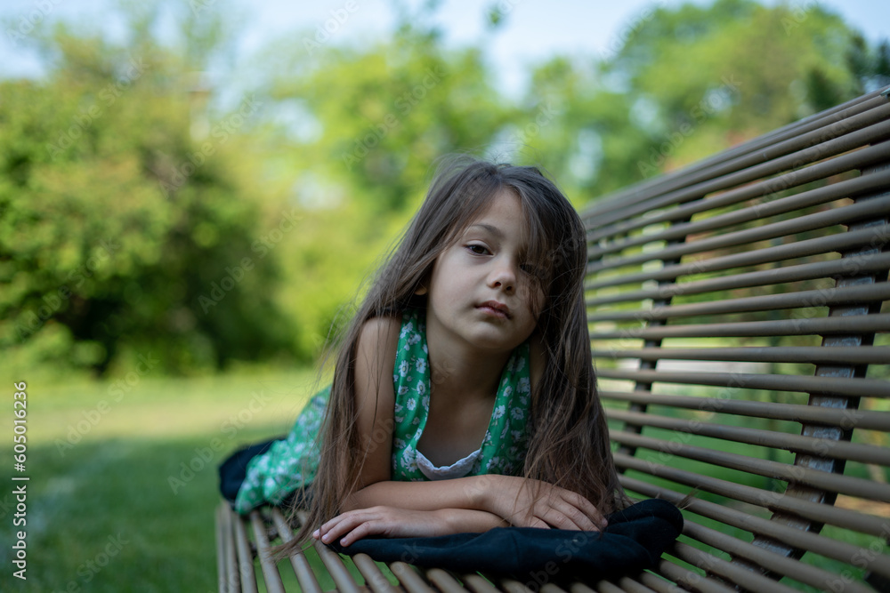 cute preschool girl smiling for portrait while laying on park bench cute preschool girl smiling for portrait while laying on park bench