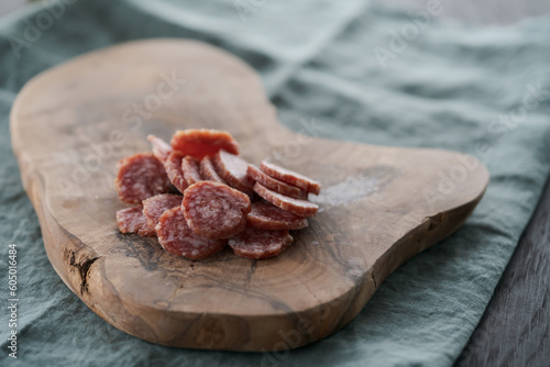 Foto Sliced cured sausage on olive serving board