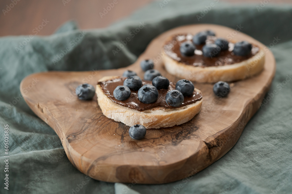 Organic chocolate hazelnut spread with fresh blueberries on ciabatta slices on wood board Organic chocolate hazelnut spread with fresh blueberries on ciabatta slices on wood board