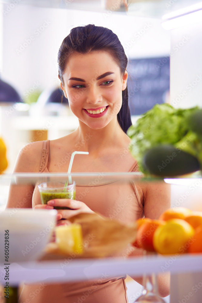 Young woman with glass of tasty healthy smoothie at table in kitchen Young woman with glass of tasty healthy smoothie at table in kitchen