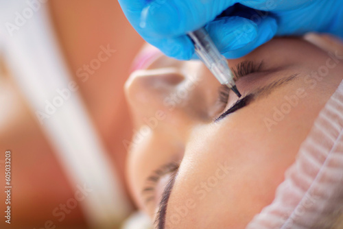 Permanent makeup for eyebrows. Closeup of beautiful woman with thick brows in beauty salon.