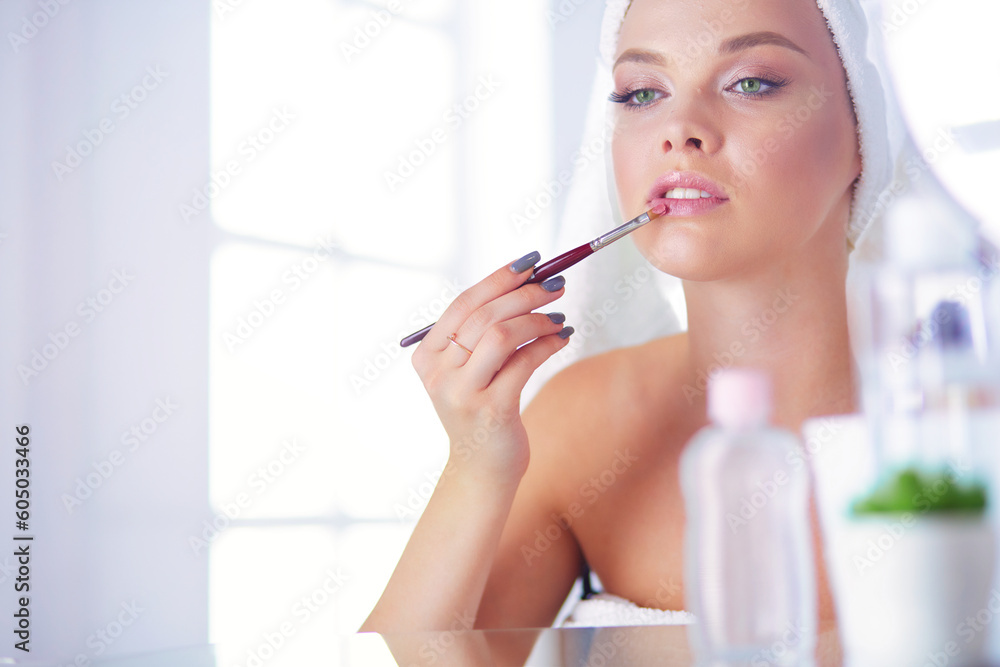 A picture of a young woman applying face powder in the bathroom A picture of a young woman applying face powder in the bathroom
