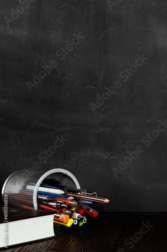 School and education concept.Copy space. Chalk board and old books. Pens and pencils in a bucket.Chalk rubbed out on blackboard. Chalkboard background vertical orientation.