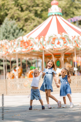 three small children are happily walking in the amusement park in the summer. International Children's Day © КРИСТИНА Игумнова