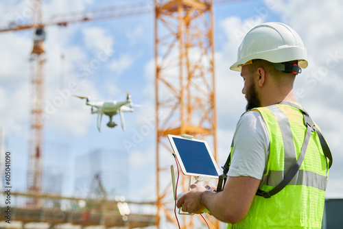 Drone operated by safety engineering inspector. Construction worker piloting drone on building site