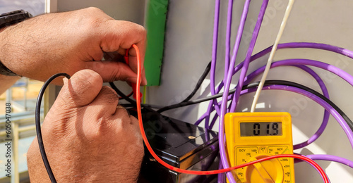 hands of an electrical technician checking with a polymeter the voltage and the correct installation of the equipment photo