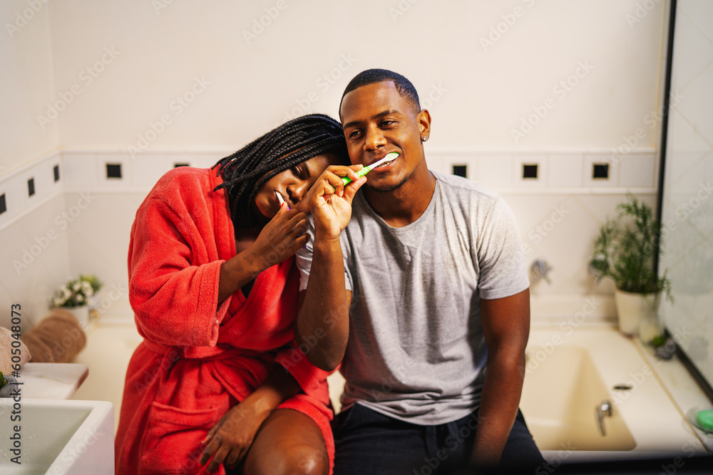 jovem casal brasileiro negro escovando os dentes juntos no banheiro sentados na banheira no dia dos namorados - obrazy, fototapety, plakaty 