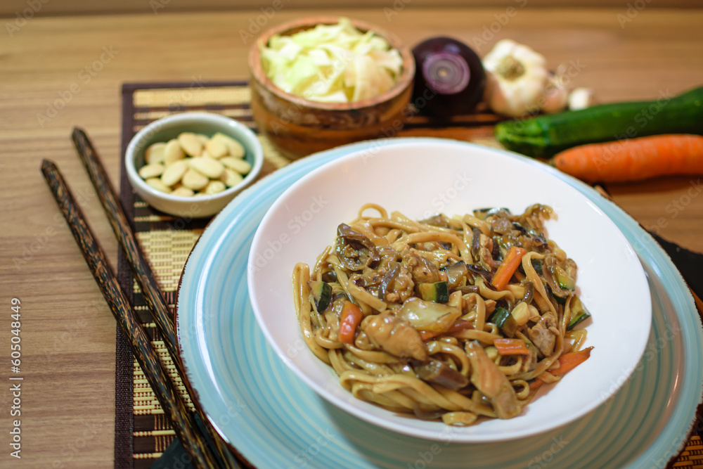 Rice noodles served with vegetables and meat in white bowl.
