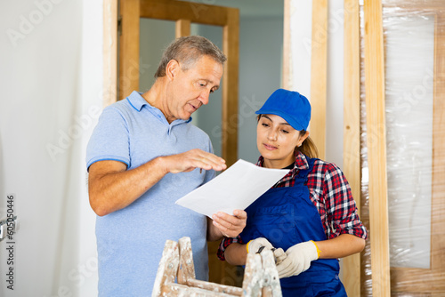 Latin woman repairer discussing project documentation with middle-aged man owner of apartment.