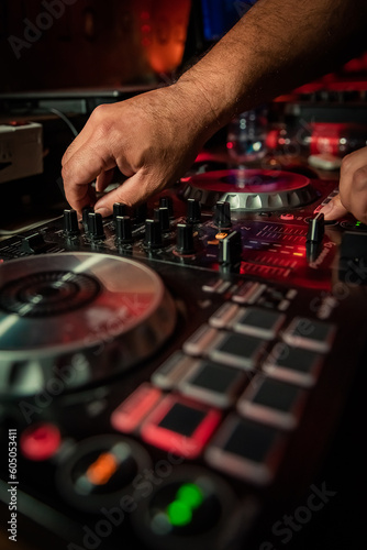 Intentionally out of focus cool DJ standing at the mixer controller, composing a new mix and making the party in a nightclub nightlife concept. dj concept. party concept. bokeh background.