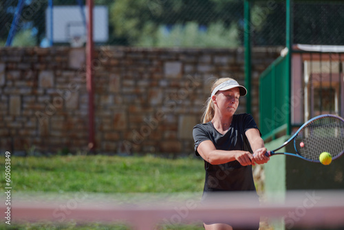 A young girl showing professional tennis skills in a competitive match on a sunny day, surrounded by the modern aesthetics of a tennis court.